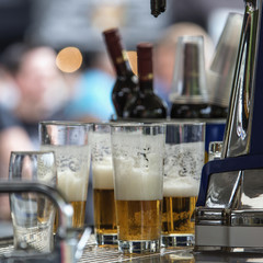 Glass glasses with beer and a bottle of wine on the bar at an open festival.
