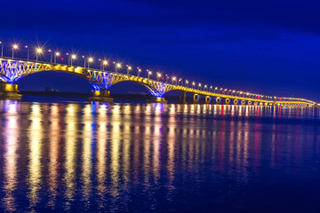 Fototapeta na wymiar an automobile bridge across the Volga River at night, illuminated by the light of lanterns, the light of which is reflected in the river