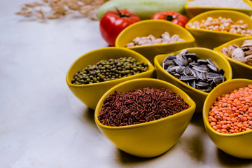 Different   grains, seeds, beans  in ceramic bowls  on  white concrete table