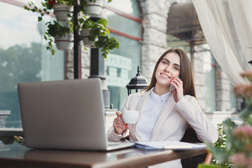 Young woman talking on phone and drinking coffee