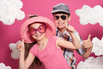 fashionable girl and boy posing on a pink background with clouds