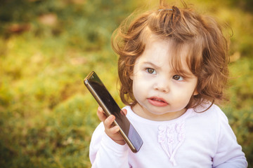 little girl with a mobile phone in the park