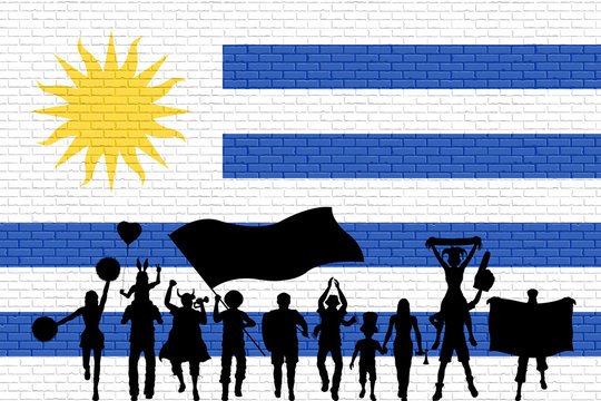 Uruguayan supporter silhouette in front of brick wall with Uruguay flag