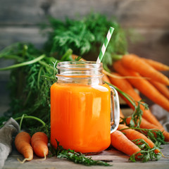 Fresh Carrot and carrot juice on Wooden Table in Garden. Vegetables Vitamins Keratin. Natural Organic Carrot lies on Wooden background.