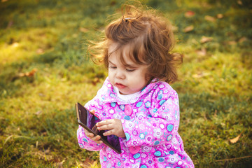 little girl with a mobile phone in the park