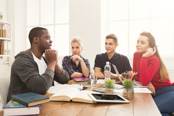 Group of diverse students studying at wooden table