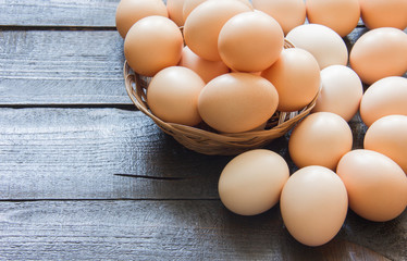 raw chicken eggs lie in a wicker basket and on a wooden table. place for text