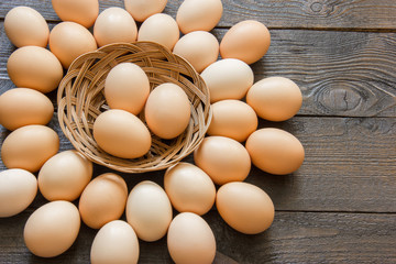 raw chicken eggs lie in a wicker basket and on a wooden table