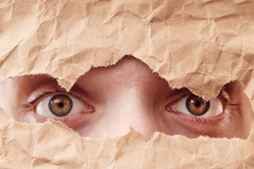Eye looking through hole in paper. Spy eye watching through a hole. Eye looking through hole in old...