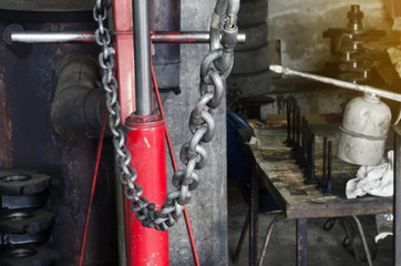 Metal chain on a red lift in a car repair shop