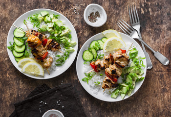 Grilled chili honey lime chicken skewers with rice and avocado salsa on wooden background, top view. Flat lay