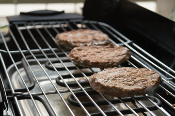Three tasty meat hamburgers cooking on electric grill. A nice day to cook at the backyard