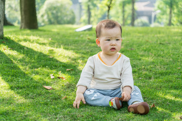 The lovely baby on the lawn is playing in the summer