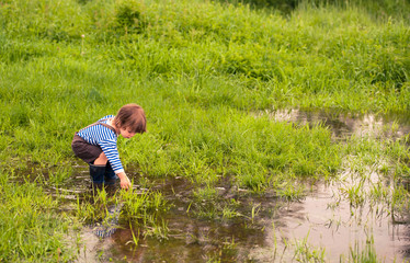 boy in shorts and rubber boots in a puddle