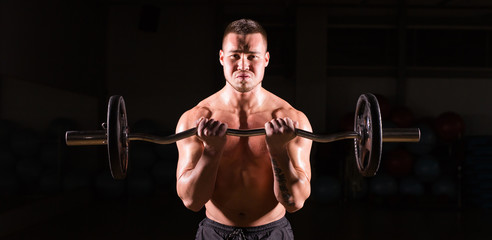 Fototapeta na wymiar Handsome power athletic man with barbell. Strong bodybuilder with six pack, perfect abs, shoulders, biceps, triceps and chest
