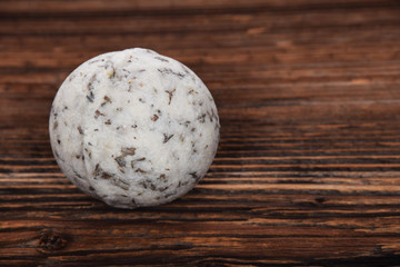 herbal white bath ball with foam in a bathtub on a brown background