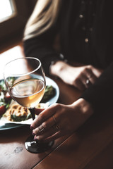 Female hand with glass of wine and food in the background