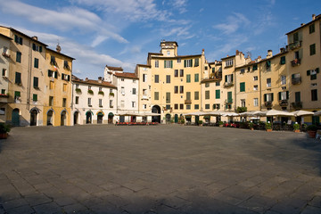 Fototapeta na wymiar Piazza Anfiteatro in the old town of Lucca. The ring of buildings surrounding the square, follows the elliptical shape of the former Roman Amphitheater of Lucca