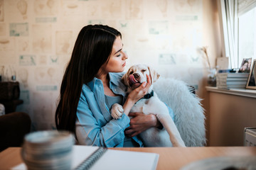 Brunette girl cuddling with puppy at home. © bnenin