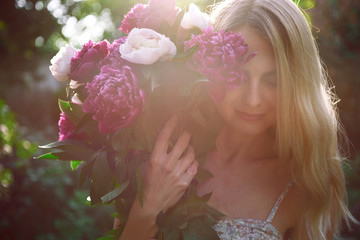 girl in the garden with a big bouquet of peonies in hands at sunset © Mykhailovskyi