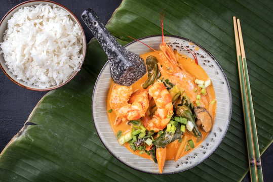 Traditionelles Thai Kaeng Phet Red Curry mit Garnelen und Reis als Draufsicht in einer Schale auf einem Bananenblatt 