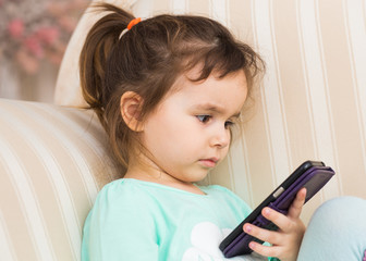 little child girl play on smartphone at home