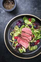 Traditional barbecue aged sliced fillet steak with lettuce and fruits as top view on a plate with copy space