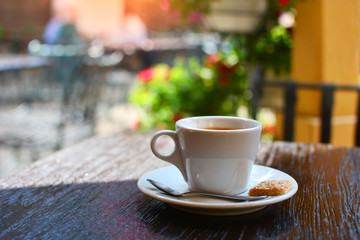 White cup of coffee in italian summer cafe. Morning coffee break in a beautiful place.