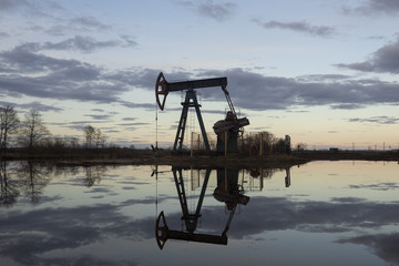 Naklejka premium Industrial pump jack, sunset in oil field