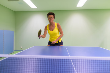Mature beautiful woman playing table tennis indoors