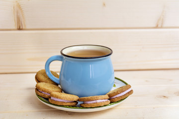 Blue Mug of Tea and Sandwich Cookies on Wooden Background