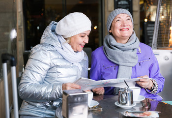 Fototapeta na wymiar Senior females reading city map in outdoors cafe
