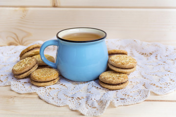 Blue Mug of Tea and Sandwich Cookies on Wooden Background