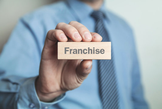 Businessman showing Franchise word in wooden block.