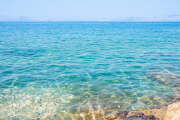 Naklejka na ściany i meble Crystal clear turquoise sea waters of a pebble beach. ionian island in Greece