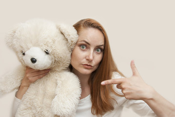 Red-Haired Young Woman in White dress Holding Ivory Soft Toy Teddy Bear Isolated Copy space. Education. Parenting. Play.