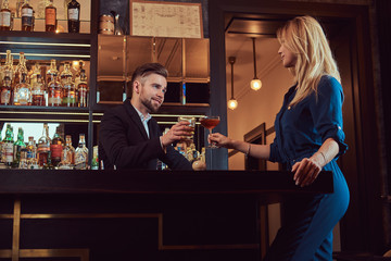 Stylish couple is spending the evening in a romantic setting, drinking wine at the bar counter.