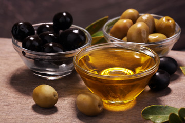 Bottle virgin olive oil and oil in a bowl with some olives