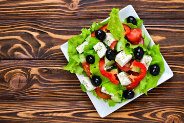 Greek salad on a wooden background. Space for text or design.
