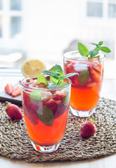 Homemade iced tea with strawberries and mint on a wooden table, vertical