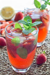 Glass of refreshing iced tea with strawberries and mint, vertical