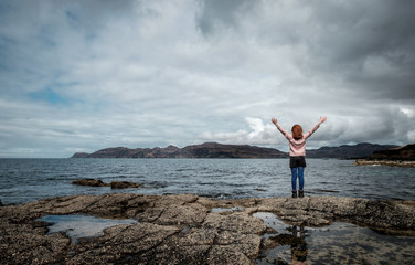 Girl with arms spread observing the views on the Scottish scenery on the Isle of Mull,