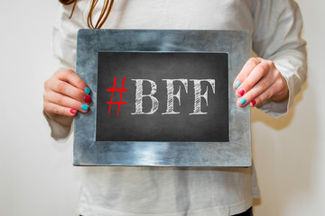 Young girl holding up blackboard with text #BFF