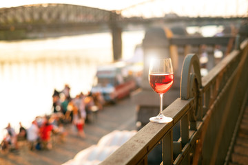 Glass of red wine on a railing with sunset in a Prague city. Concept of free time in the city and...