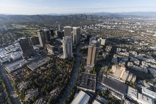 Aerial view of Los Angeles Century City towers and Olympic Bl with Beverly Hills and the Santa Monica Mountains in background.