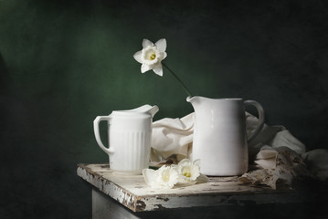 
Still life with daffodils and two white jugs on a green background