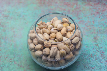 Bowl of pistachios in shell on green rusty background
