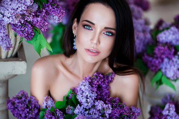 Beauty portrait. Beautiful woman with sensual lips sitting among violet flowers. Cosmetics,...