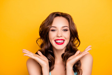 Portrait of cheerful positive girl with modern hairdo laughing gesturing with hands looking at camera enjoying daydream isolated on yellow background