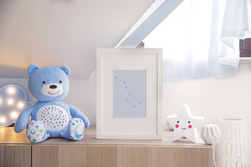 The modern sandinavian newborn baby room with mock up poster frame, teddy bear and star. Sunny and bright interior.